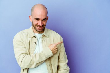 Mor arka planda izole edilmiş beyaz kel bir adam gülümsüyor ve boş alanda bir şeyler gösteriyor..
