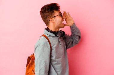 Pembe arka planda izole edilmiş genç bir öğrenci bağırıyor ve avuç içini açık tutuyor..