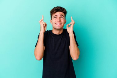 Kafkasyalı genç adam mavi arka planda izole edilmiş şans dilemek için şans diliyor.