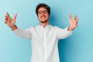 Kafkasyalı genç iş adamı mavi arka planda izole edilmiş kameraya sarıldığı için kendinden emin..