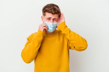 Koronavirüs maskesi takan genç adam beyaz arka planda inliyor ve ağlıyordu..