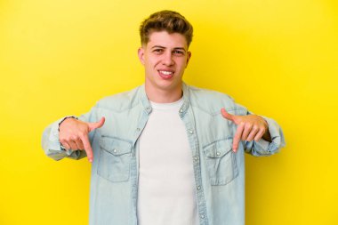 Sarı arka planda izole edilmiş genç beyaz adam parmakları aşağıda, olumlu bir his var..