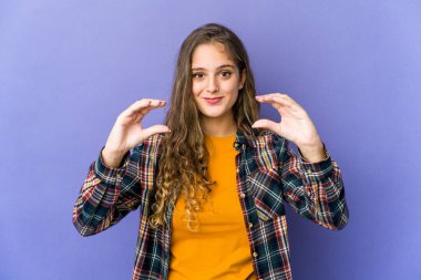 Beyaz tenli hoş bir kadın elinde avuç içi bir şeyle kameraya sunuyor..