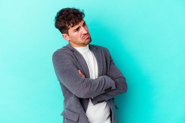 Mavi arka planda izole edilmiş genç beyaz adam tekrarlanan bir görevden yoruldu..