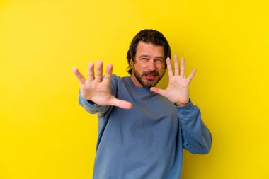 Sarı arka planda izole edilmiş orta yaşlı beyaz bir adam yakın bir tehlike nedeniyle şoka uğruyor.