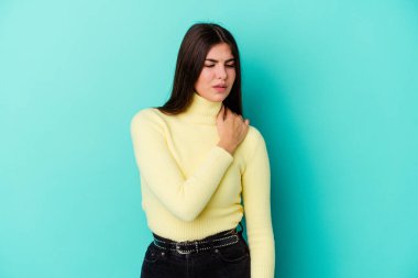 Mavi arka planda izole edilmiş, omuz ağrısı olan beyaz bir kadın..