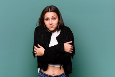 Mavi arka planda izole edilmiş genç Hintli kadın omuzlarını silker ve gözleri açık kalır..