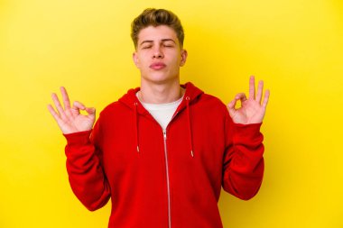 Sarı arka planda izole edilmiş genç beyaz adam sıkı çalışma gününden sonra rahatlıyor. Yoga yapıyor..