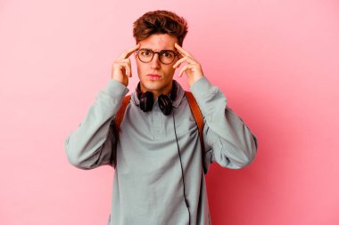 Pembe arka planda izole edilmiş genç bir öğrenci bir göreve odaklanmış, işaret parmaklarını işaret ediyor..