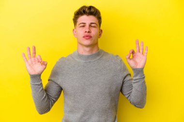 Sarı arka planda izole edilmiş genç beyaz adam sıkı çalışma gününden sonra rahatlıyor. Yoga yapıyor..