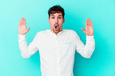 Kafkasyalı genç bir adam mavi arka planda izole edilmiş. Bir fikri, ilham verici bir fikri var..