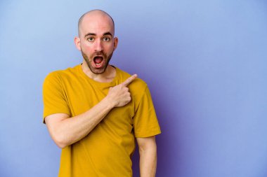 Mor arka planda izole edilmiş genç, beyaz, kel bir adam.
