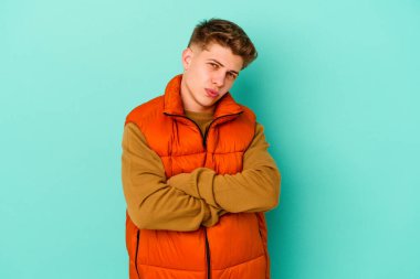 Mavi arka planda izole edilmiş, sıkılmış, yorgun ve dinlenmeye ihtiyacı olan genç beyaz bir adam..