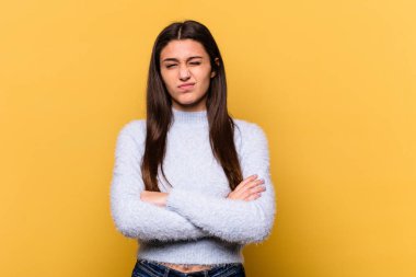 Sarı arka planda izole edilmiş genç Hintli kadın alaycı bir ifadeyle kameraya bakıyor..