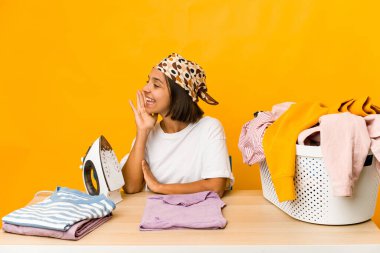 Giysileri ütüleyen, bağıran ve ağzı açık olan genç İspanyol kadın..