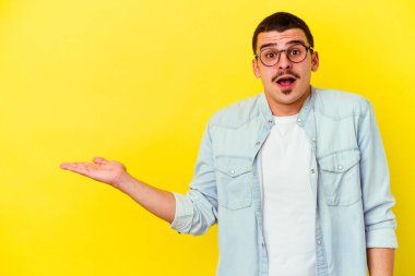 Sarı arka planda izole edilmiş beyaz bir adam, avuç içinin fotokopi alanını tutmaktan etkilenmiş..