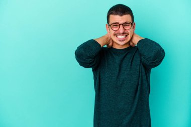 Kafkasyalı genç adam mavi arka planda izole edilmiş kafasının arkasına dokunuyor, düşünüyor ve bir seçim yapıyor..