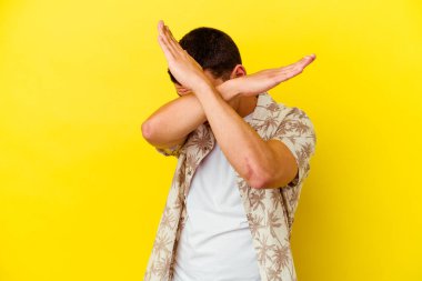 Sarı arka planda izole genç beyaz adam iki kolu çapraz tutuyor, inkar kavramı.