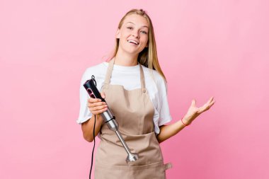 Genç Rus aşçı elinde elektrikli mikser tutarak zaferi ya da başarıyı kutluyor..