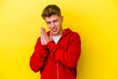 Sarı arka planda izole edilmiş genç beyaz adam enerjik ve rahat hissediyor, ellerini ovuşturuyor kendinden emin..