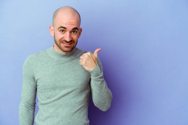 Mor arka planda izole edilmiş beyaz saçlı genç adam işaret parmağıyla fotokopi alanını işaret ederek şok oldu..