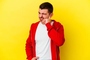 Sarı arka planda izole genç beyaz adam parmaklarıyla kulakları örtüyor, stresli ve umutsuz yüksek sesli bir ortam tarafından.