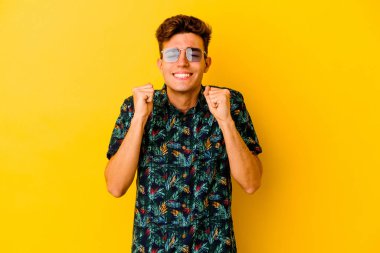 Hawaii gömleği giyen genç beyaz adam sarı arka planda izole edilmiş mutlu ve başarılı hissediyor. Zafer konsepti.
