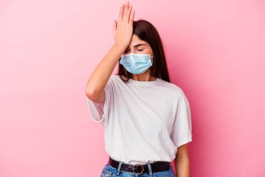 Pembe arka planda izole edilmiş virüs maskesi takan beyaz bir kadın bir şeyi unutuyor. Alnına avuç içi ve kapalı gözlerle vuruyor..