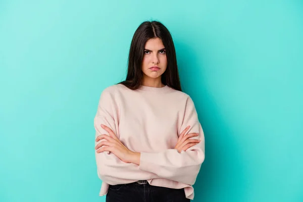 Young caucasian woman isolated on blue background blows cheeks, has tired expression. Facial expression concept.