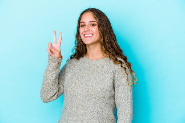 Молодая кавказская вьющиеся волосы женщина изолированы показывая знак победы и широко улыбаясь.