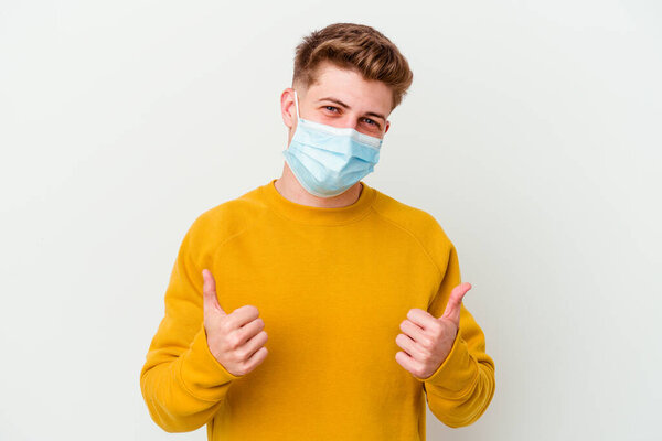 Young man wearing a mask for coronavirus isolated on white background raising both thumbs up, smiling and confident.