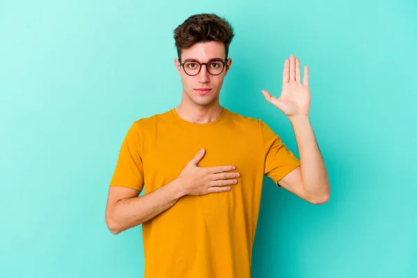Young Caucasian Man Isolated Blue Background Taking Oath Putting Hand — Stock Photo, Image