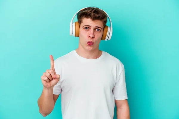 Ung Kaukasier Man Lyssnar Musik Med Hörlurar Isolerade Blå Bakgrund — Stockfoto