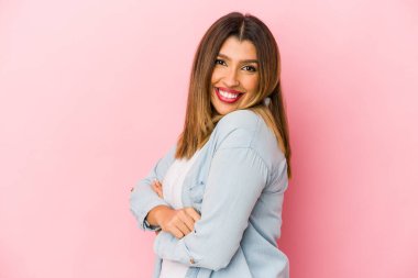 Pembe arka planda izole edilmiş genç Hintli kadın mutlu, güler yüzlü ve neşeli..
