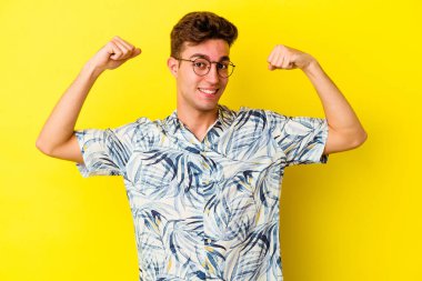 Sarı arka planda izole edilmiş genç beyaz adam güçlü bir hareket sergiliyor, kadınsı gücün sembolü.