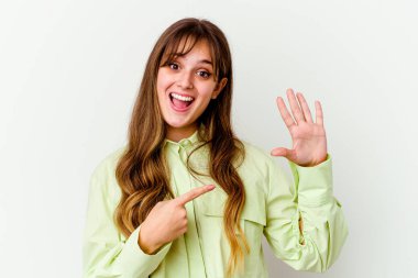 Beyaz arka planda izole edilmiş beyaz tenli hoş bir kadın gülümseyerek beş numarayı parmaklarıyla gösteriyor..