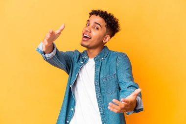 Genç Afro-Amerikalı kıvırcık adam mor üzerine izole edilmiş kameraya sarılıyor..