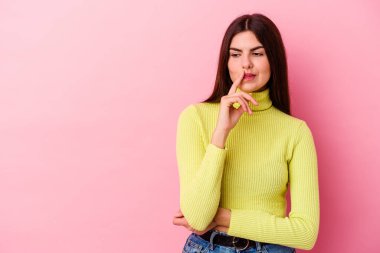 Pembe arka planda soyutlanmış beyaz bir kadın şüpheli ve şüpheci bir ifadeyle yana bakıyor..