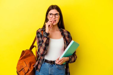 Sarı arka planda izole edilmiş, tırnak yiyen, gergin ve endişeli genç bir bayan..