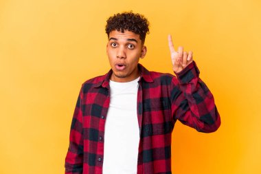 Genç Afro-Amerikalı kıvırcık adam mor renkte, ağzı açık, üst tarafı işaret ediyor..