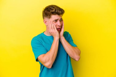 Sarı arka planda izole edilmiş genç beyaz adam korkmuş ve korkmuş..