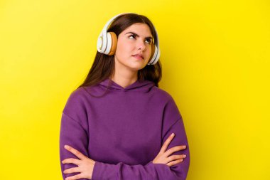 Pembe arka planda izole edilmiş kulaklıklarla müzik dinleyen genç beyaz kadın tekrarlanan bir görevden bıktı..