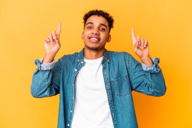 Mor üzerine izole edilmiş genç Afro-Amerikalı kıvırcık adam iki parmağını da havaya kaldırmış boş bir alan gösteriyor..