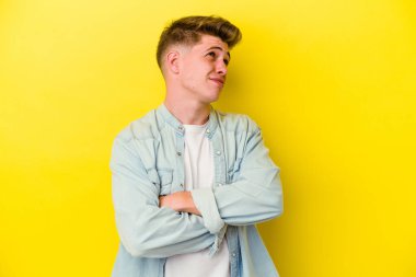 Sarı arka planda izole edilmiş genç beyaz adam hedeflere ve amaçlara ulaşma hayali kuruyor.