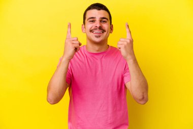 Sarı arka planda izole edilmiş beyaz bir adam iki parmağı da boş bir alan gösteriyor..