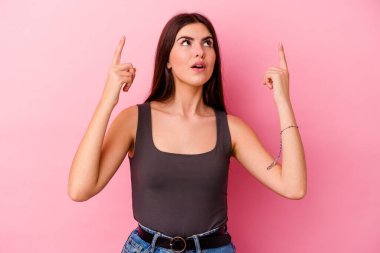 Pembe arka planda izole edilmiş beyaz bir kadın ağzı açık bir şekilde üst tarafı işaret ediyor..