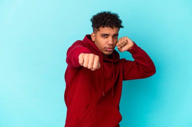 Genç Afro-Amerikan kıvırcık adamı, mavi üzerine izole edilmiş bir şekilde bir tartışma yüzünden yumruk atıyor, sinirleniyor ve kavga ediyor..