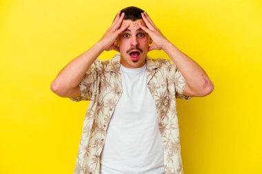 Sarı arka planda izole edilmiş beyaz bir adam yüzünün yarısını palmiye ile kaplayarak eğleniyor..