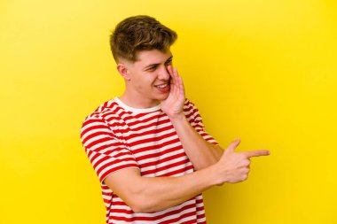 Sarı arka planda izole edilmiş genç beyaz bir adam bir dedikodu söylüyor, bir haber sunuyor..