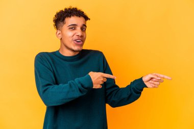 Genç Afro-Amerikan kıvırcık adamı, mor noktalar üzerinde izole edilmiş, bir fotokopi alanına işaret ediyor, heyecan ve arzusunu ifade ediyor..